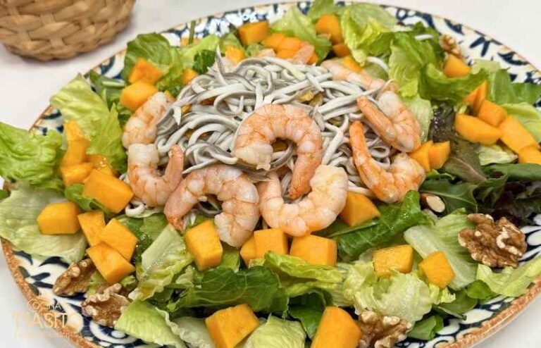 Ensalada de gulas y gambones con hojas verdes, melocotón y frutos secos