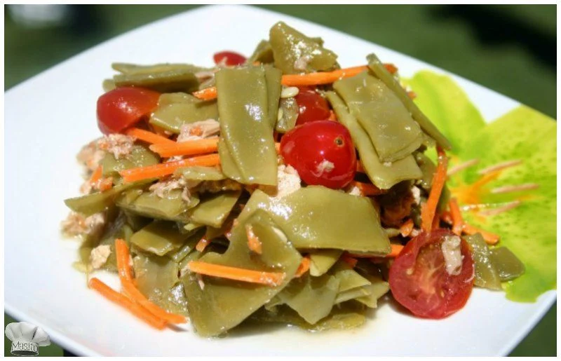Ensalada de judías verdes con atún, servida en un plato con tomates cherry y aliño de aceite de oliva