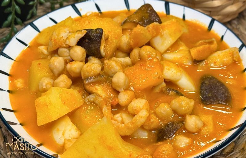 Patatas guisadas con sepia y garbanzos servidas en un plato hondo, con caldo dorado y trozos de sepia tierna