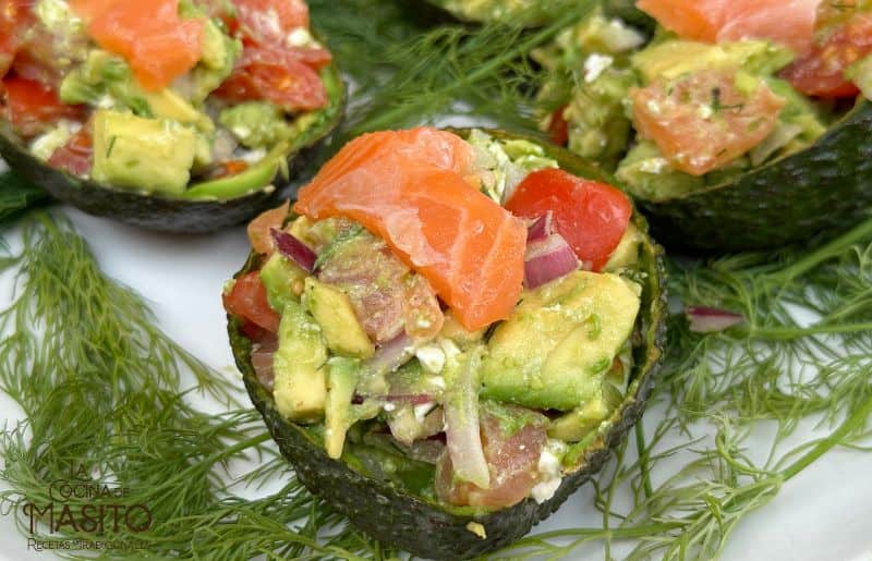 Aguacates rellenos de salmón ahumado servidos en un plato blanco, decorados con eneldo fresco y rodajas de limón.