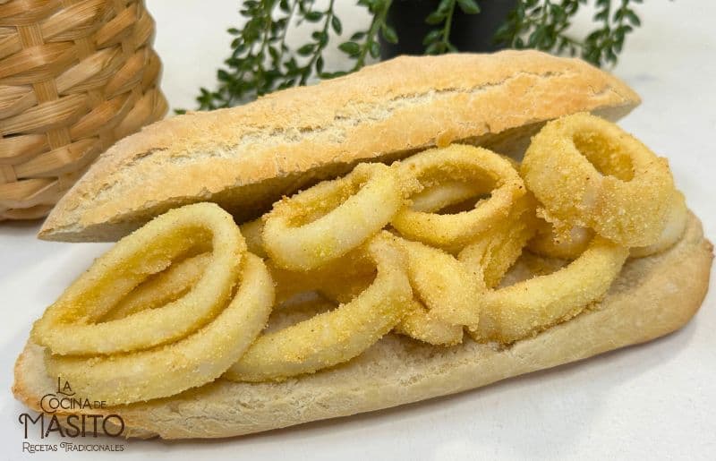 Bocadillo de calamares tradicional servido con pan crujiente y rodajas de limón fresco.