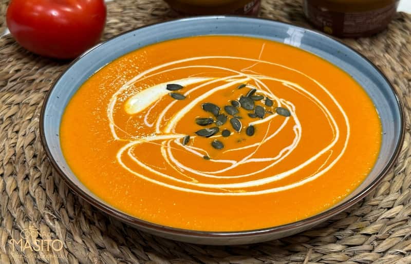 Tazón de crema de tomates asados adornada con hierbas frescas y semillas