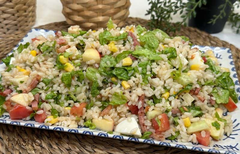 Ensalada de arroz colorida con verduras frescas, maíz y aliño ligero en un bol blanco.