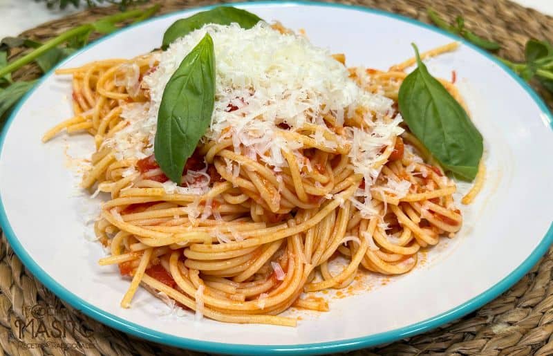 Plato de espaguetis all'arrabbiata servido con una salsa de tomate picante, ajo y perejil fresco, ideal para amantes de los sabores intensos.