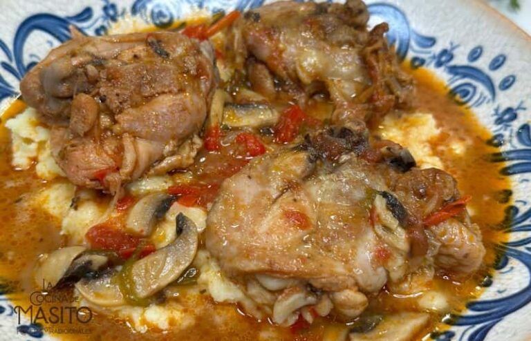 Imagen de un suculento plato de pollo en salsa de tomate y champiñones, servido en un plato blanco con hierbas frescas como decoración.