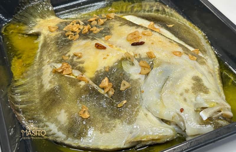 Imagen de un rodaballo a la bilbaína servido con su deliciosa guarnición de ajos y guindillas.