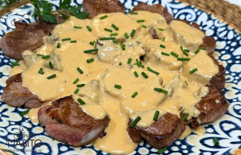 Solomillo de cerdo bañado en una cremosa salsa de queso azul servido en un plato elegante.