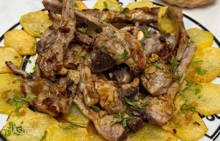 Chuletas de cordero al ajillo acompañadas de patatas doradas, una receta tradicional y llena de sabor.