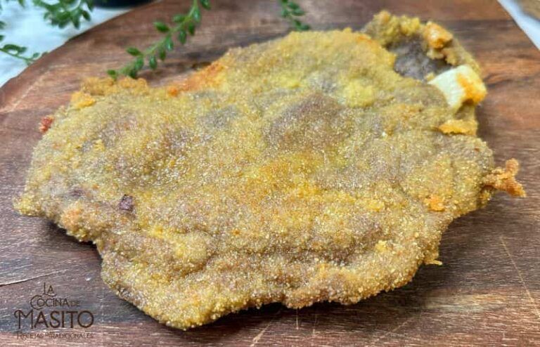 Fotografía de un cachopo asturiano crujiente, acompañado de patatas fritas y pimientos asados.