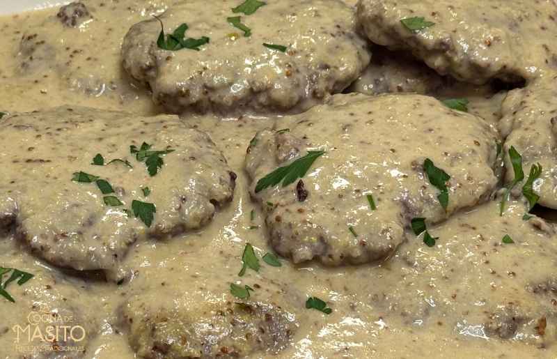 Foto de filetes rusos bañados en una cremosa salsa de miel y mostaza, acompañados de guarnición.