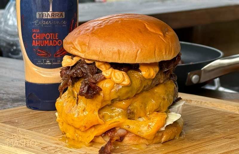Jugosa hamburguesa de buey con salsa de chipotle ahumado, acompañada de pan artesanal y guarnición.