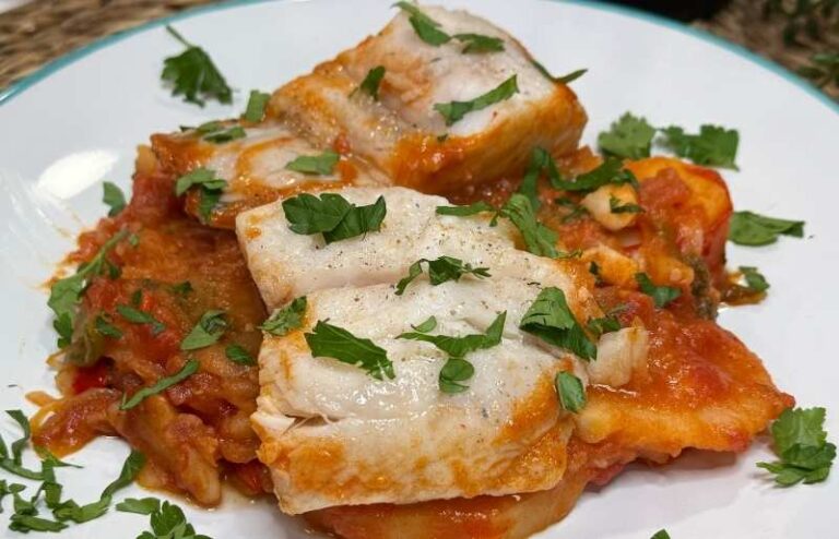 Merluza a la arriera con pimientos, tomate y ajo, presentación en una cazuela rústica.