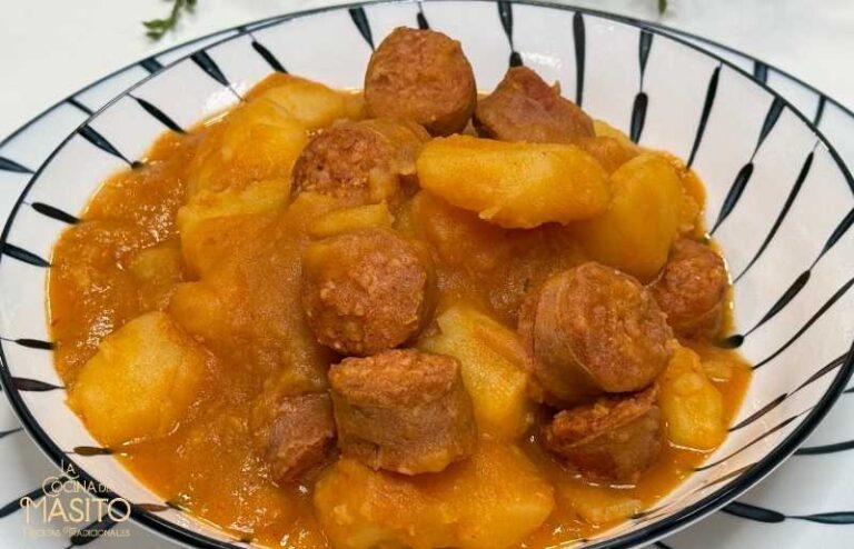 Plato de patatas a la riojana servido en un cuenco, acompañado de chorizo ​​y pimientos.