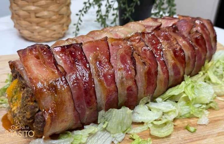 Rollo de carne picada relleno de espinacas servido en una tabla de madera con guarnición de ensalada fresca.