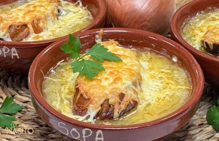 Un cuenco humeante de sopa de cebolla francesa gratinada con queso derretido y crujiente pan tostado.