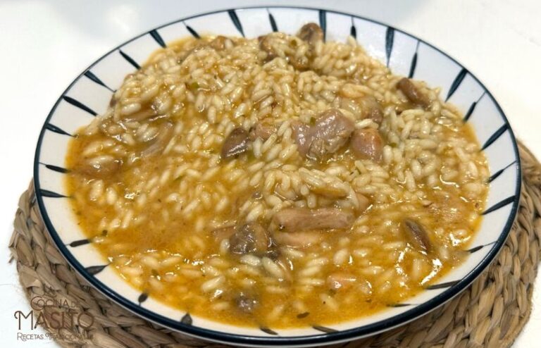 Plato de arroz meloso con costillas adobadas y contramuslos de pollo, con una textura cremosa y sabor intenso.