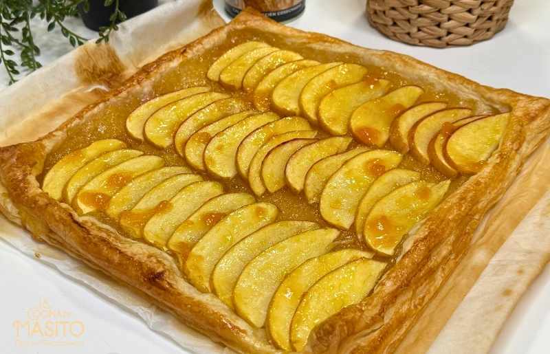 Fotografía de un hojaldre dorado y crujiente relleno de manzana y cabello de ángel, recién horneado y listo para servir.