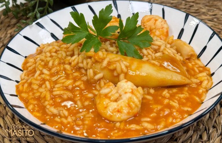 Plato de arroz meloso con chipirones y langostinos al ajillo, servido en un cuenco con una textura cremosa y un intenso sabor a marisco.