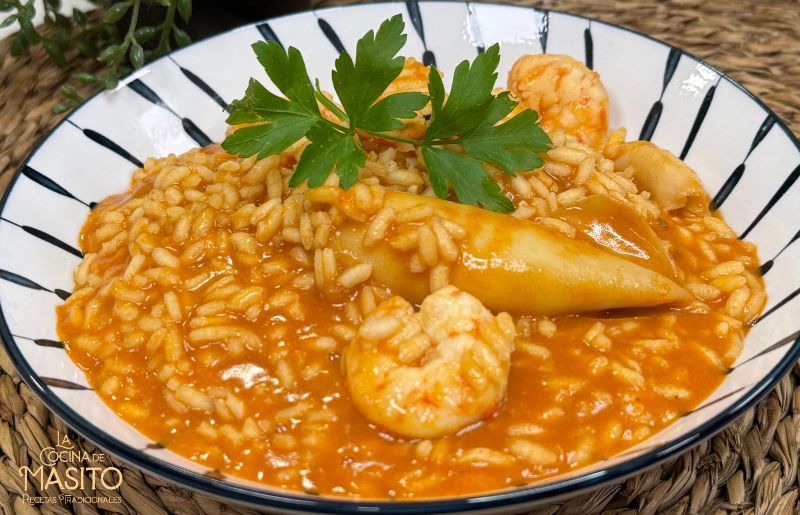 Plato de arroz meloso con chipirones y langostinos al ajillo, servido en un cuenco con una textura cremosa y un intenso sabor a marisco.
