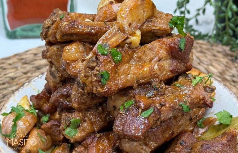 Costillas de cerdo doradas y crujientes al ajillo, cocinadas en sartén con ajo y especias, listas para servir con una guarnición.