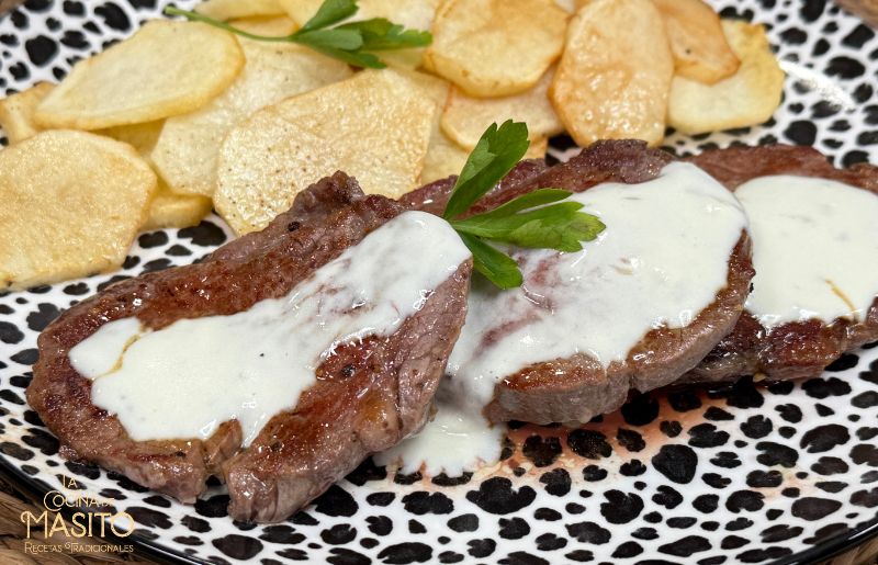 Plato de solomillo de ternera al roquefort con salsa cremosa, acompañado de guarnición de patatas.