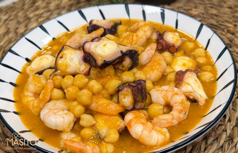 Plato de garbanzos con pulpo y langostinos servido en cazuela de barro