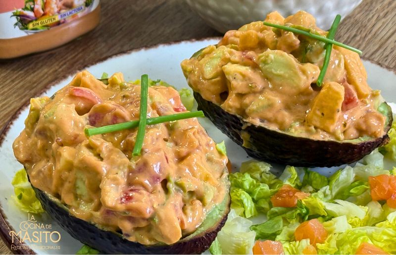 Mitades de aguacate rellenas de salmón y salsa cocktail decoradas con cebollino