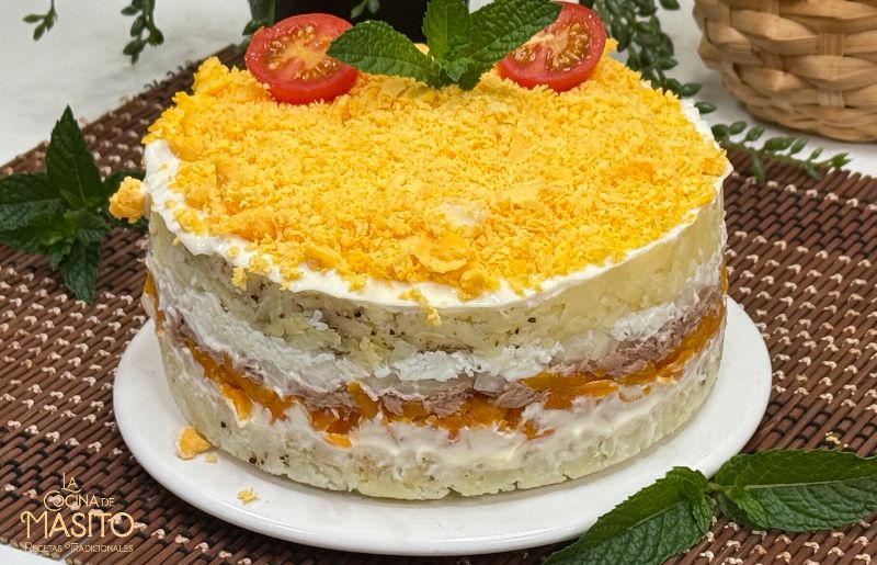 Primer plano de ensaladilla mimosa decorada con yema rallada, patata, zanahoria y mayonesa
