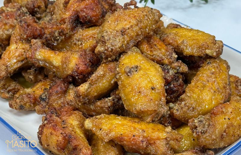 Alitas de pollo lemon pepper crujientes, servidas con salsa de limón y especias.