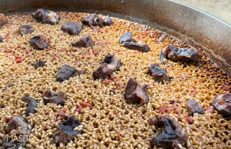 Paella de osobuco de ternera servida en paellera, con arroz y trozos de carne desmenuzada.