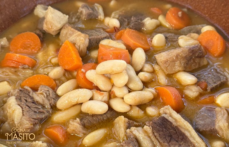 Primer plano de fabes con costillas de ternera recién hechas, con salsa melosa y costillas doradas.