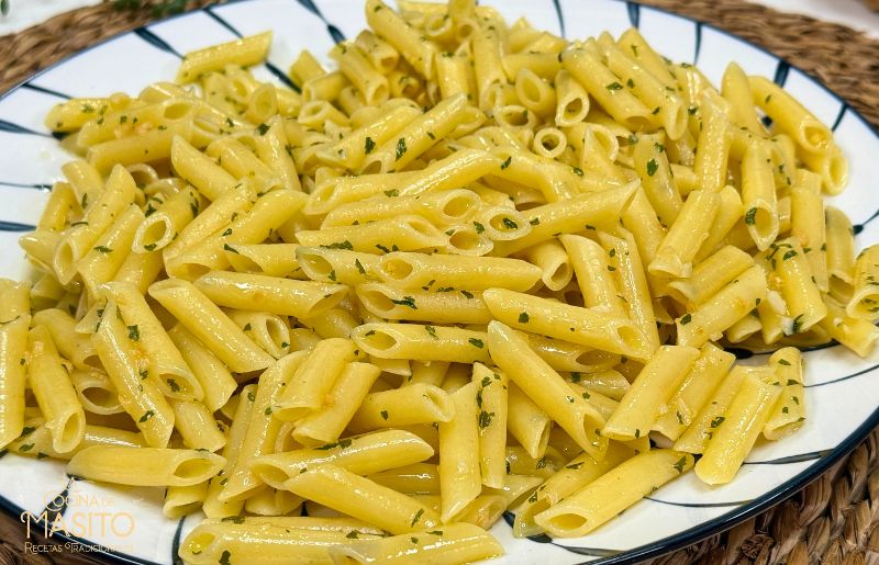 Macarrones al aglio e olio con ajo dorado y cayenas, servidos en plato blanco.