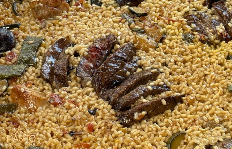 Detalle de una paella de entraña de ternera con arroz dinamita y setas shiitake.