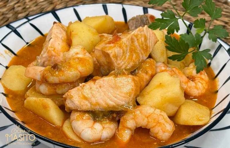 Guiso de patatas con salmón y langostinos servido en plato hondo