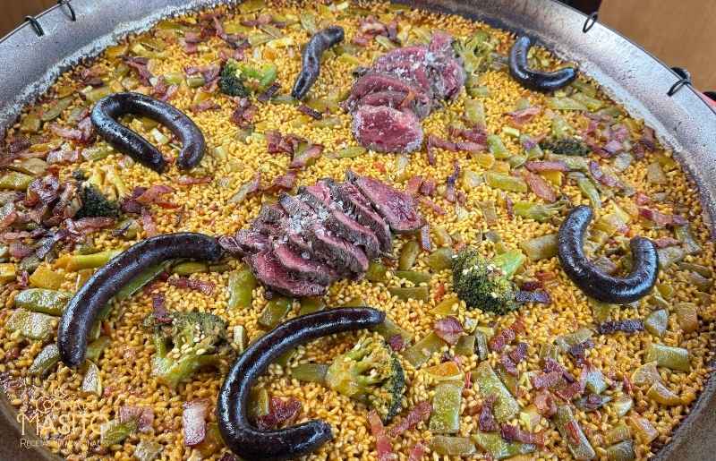 Detalle del arroz de la paella de solomillo de ternera con trozos de carne, bacon y verduras.